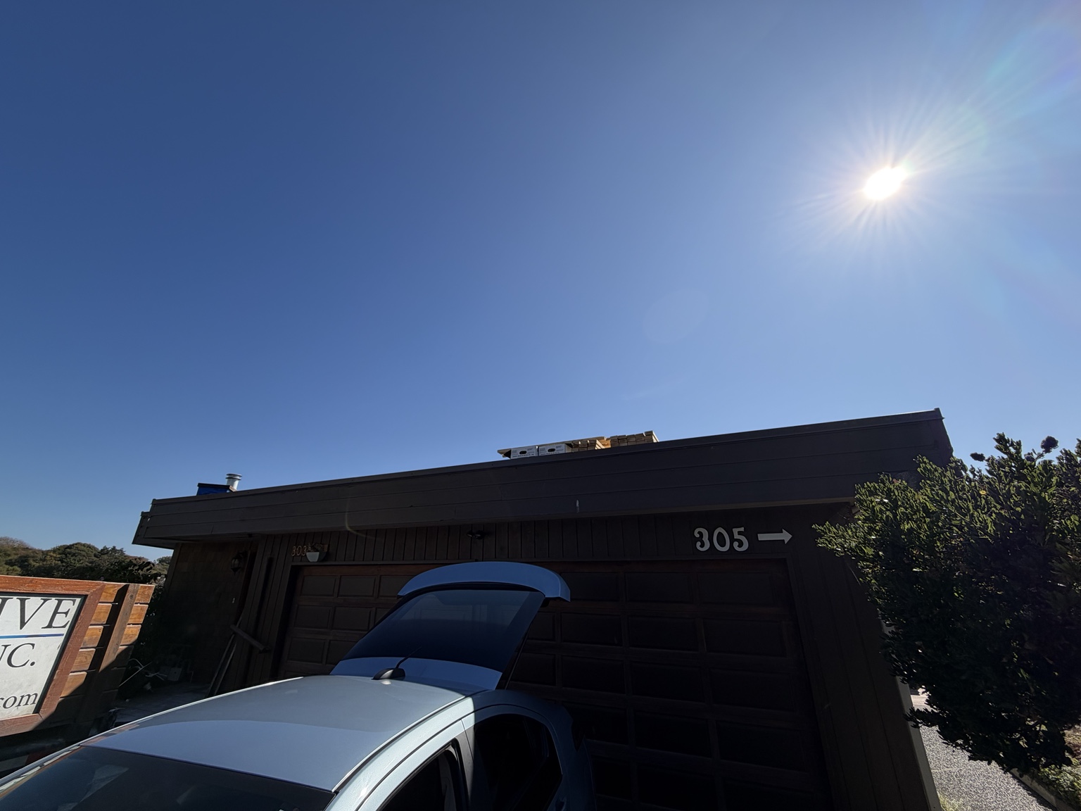 Flat roof seen from below with dark wood fascia above a driveway and garage doors
